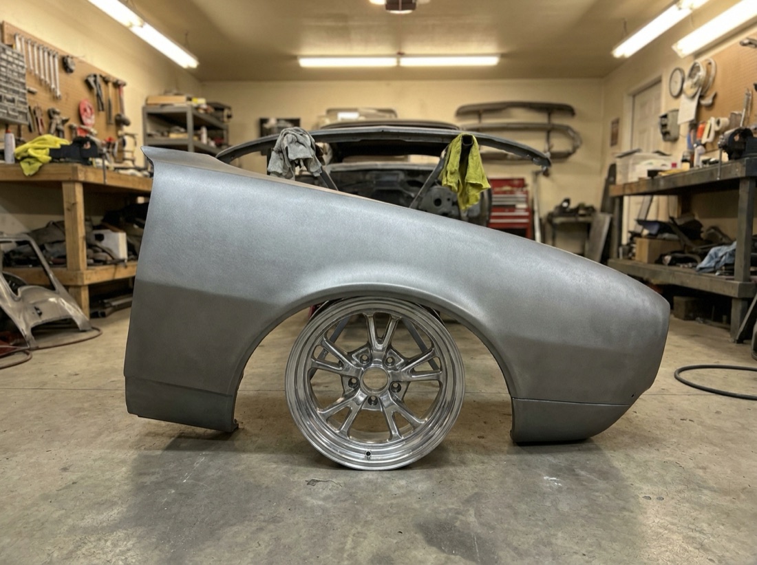 Classic car fender media-blasted to bare metal in a restoration garage